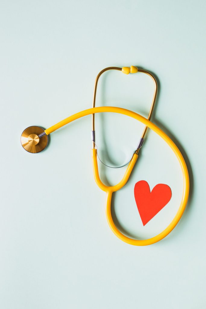 A stethoscope with a paper heart next to it.